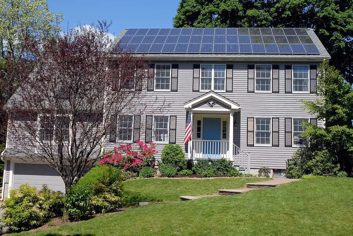 Solar panels cover the sloping roof of a suburban home.