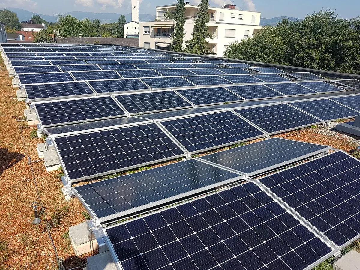 Photovoltaic panels on a flat roof with shadows across the nearest row.