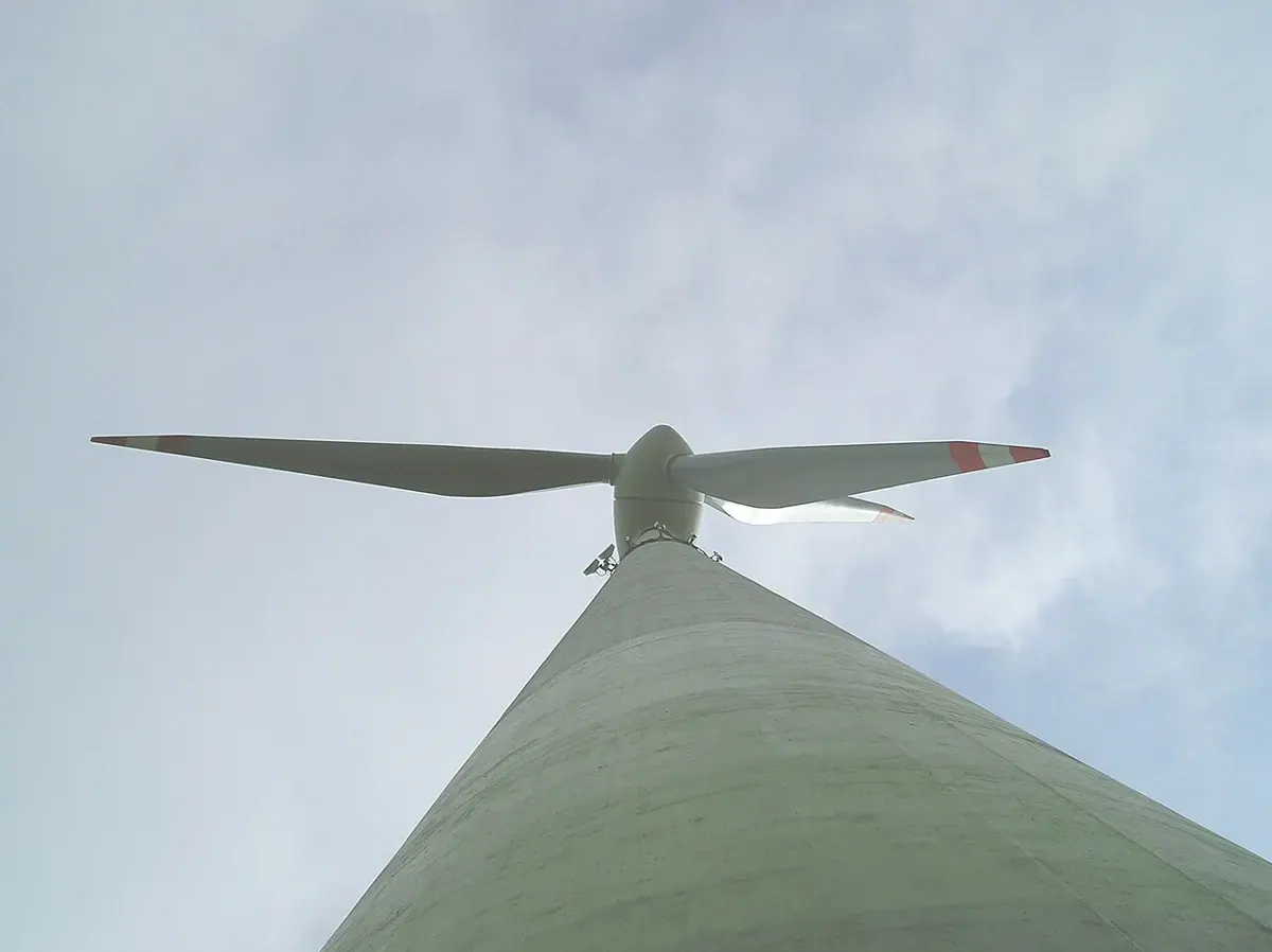 Looking up a wind turbine tower toward its rotor blades.
