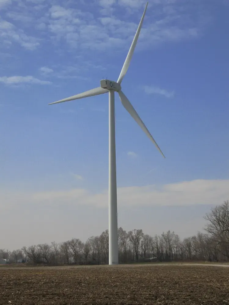 A tall wind turbine rises over an open field.