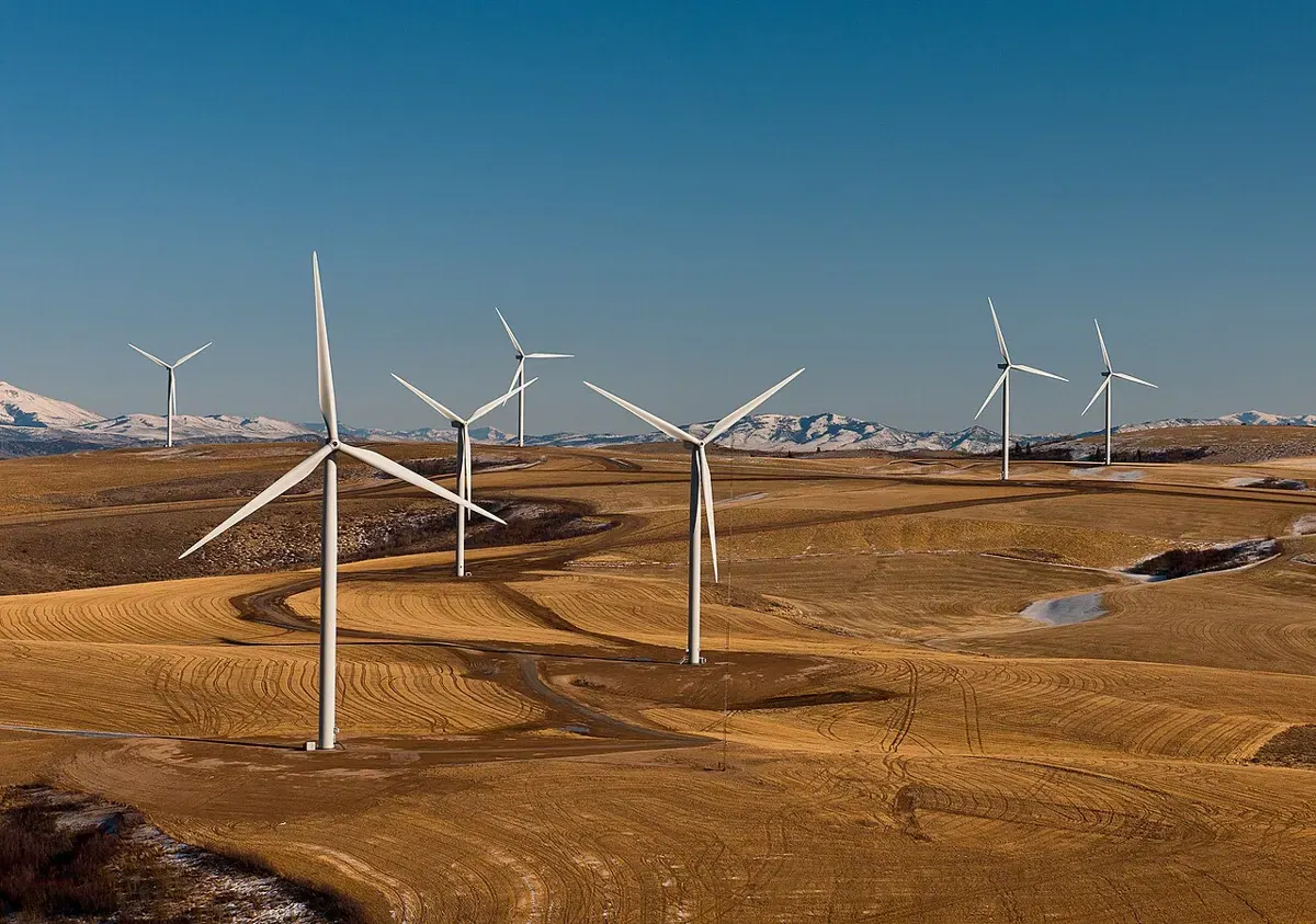An aerial view of wind turbines spread across open farmland.