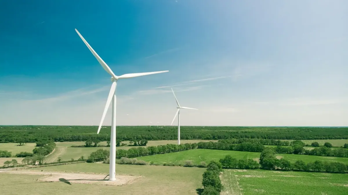 Wind turbines above green fields and woodland.