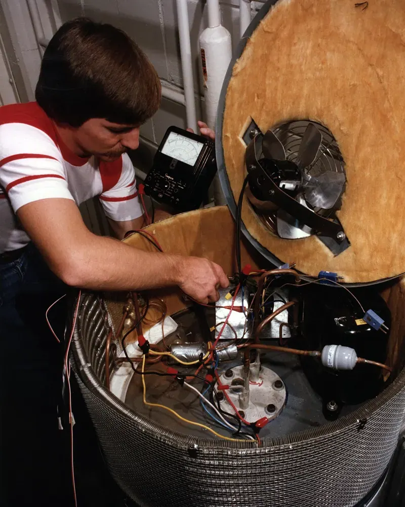 A technician works on the components of a heat-pump water heater.