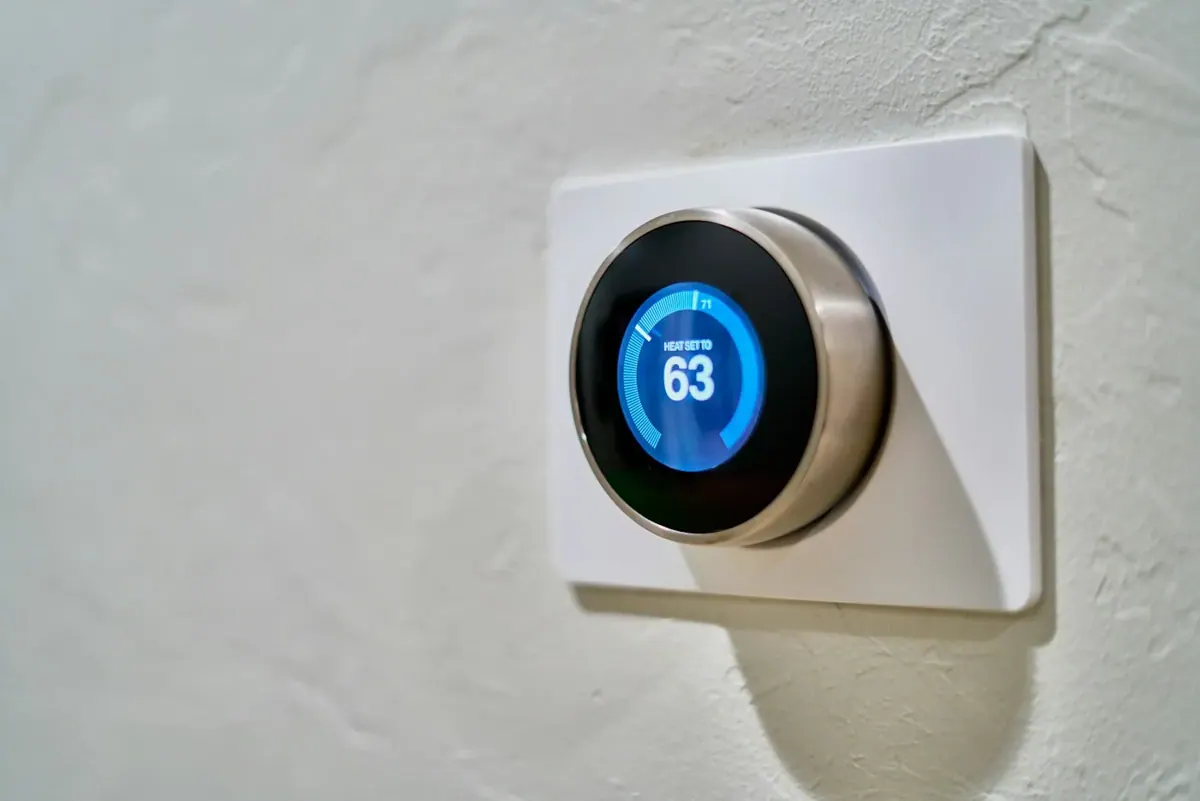 A round digital thermostat mounted on an interior wall.