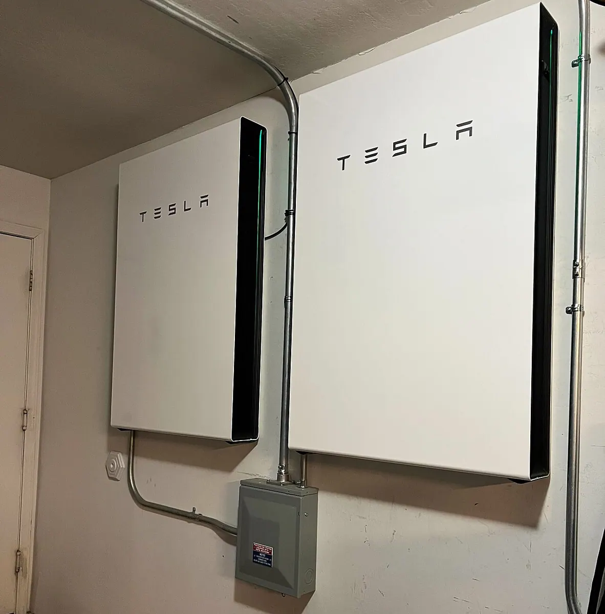 Two Tesla Powerwall home batteries installed on an interior wall.