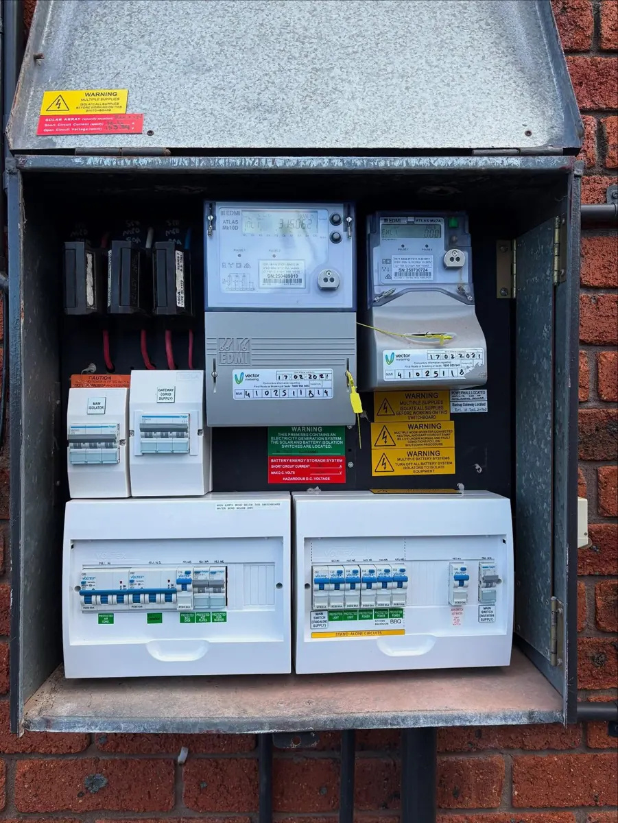 A residential solar battery installed beside a main electrical switchboard in Australia.