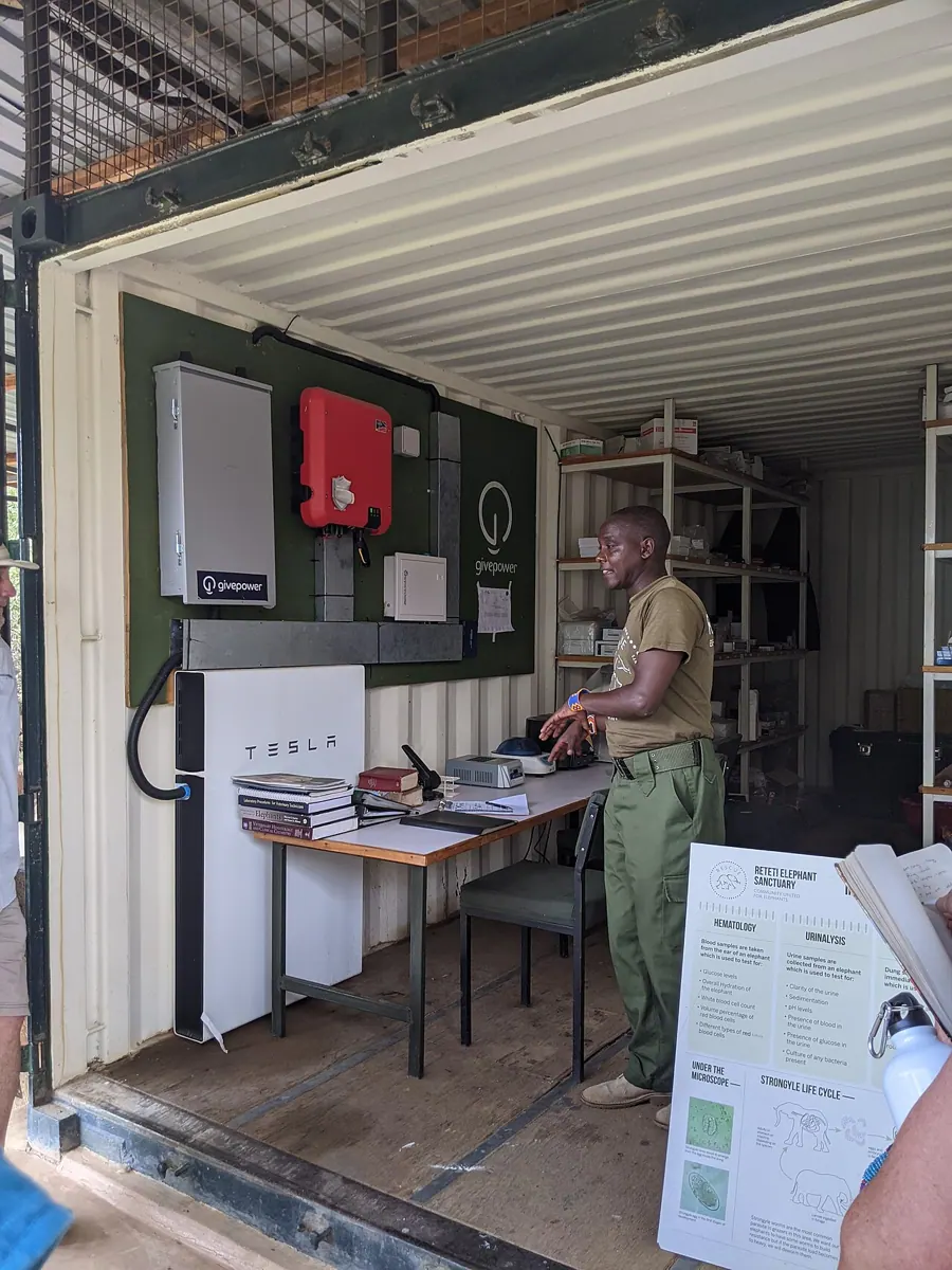 A Tesla Powerwall battery beside a technician in an energy equipment room in Kenya.