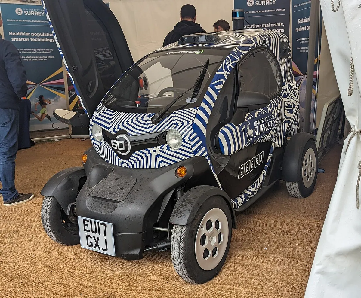 A small Renault Twizy electric vehicle on display at an indoor event.