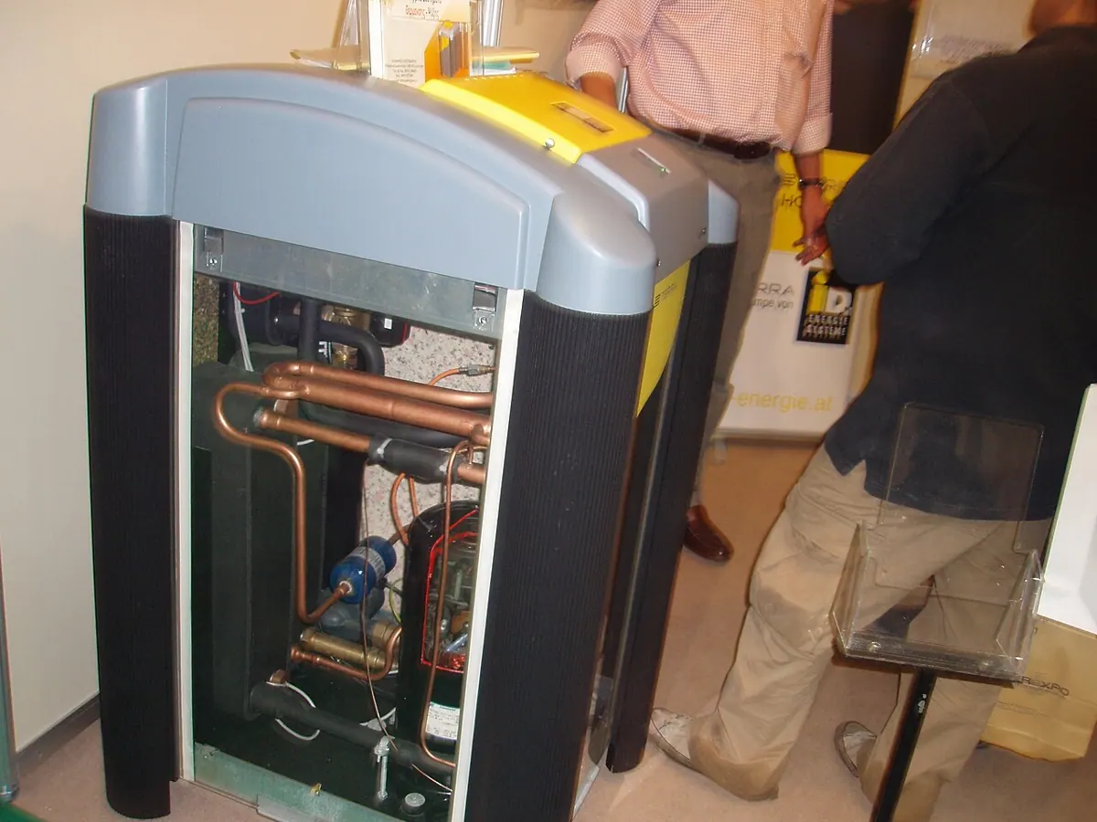 The open cabinet of a ground-source heat pump shows internal pipework.