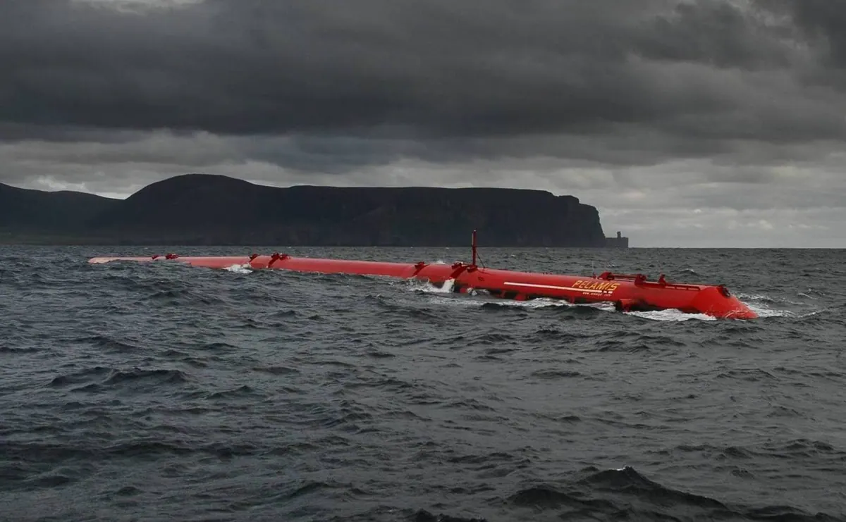 A red Pelamis wave energy converter floats at sea.