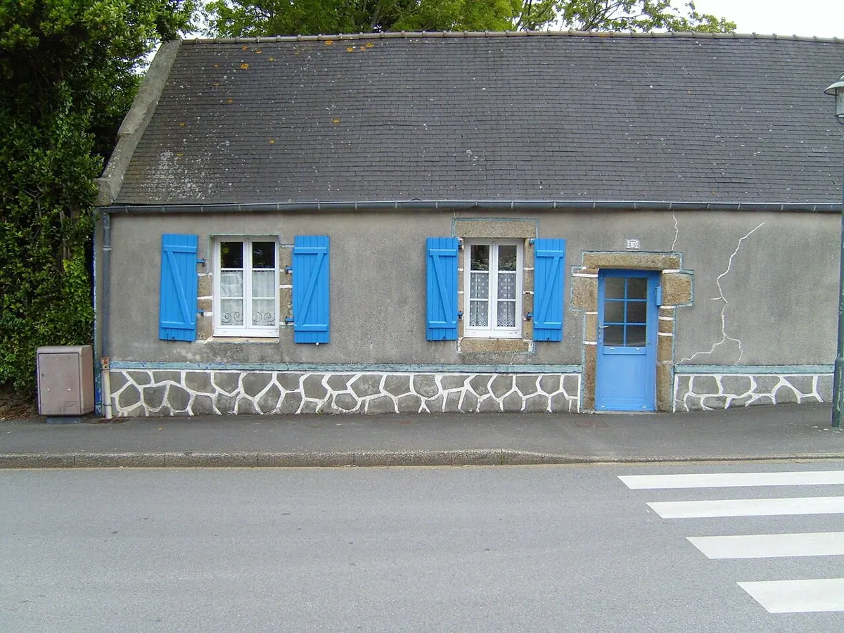 Blue shutters surround a window on a house in Brittany.