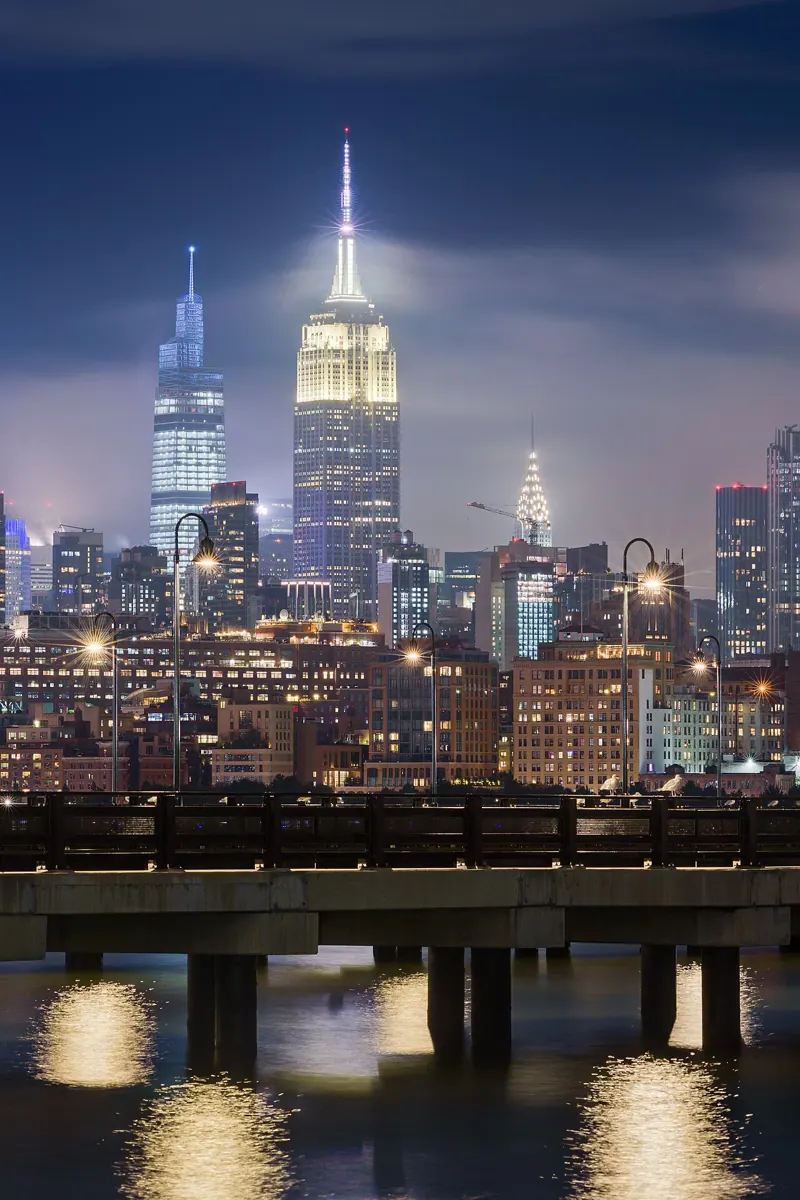 Illuminated Manhattan buildings seen across the water from Jersey City at night.